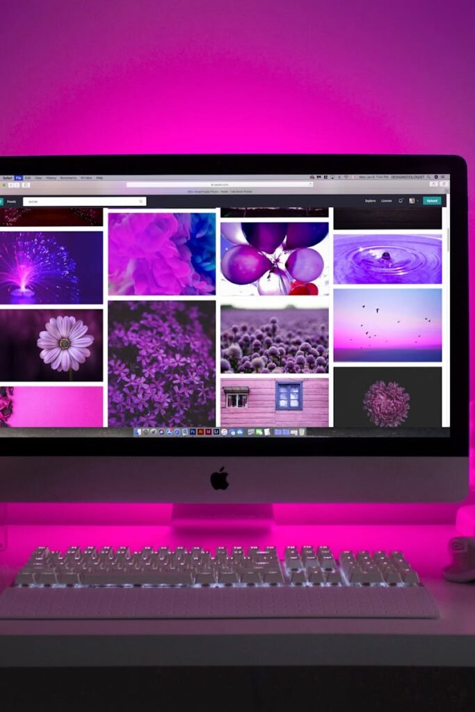 Modern desk setup with neon lighting and a desktop computer displaying colorful images.